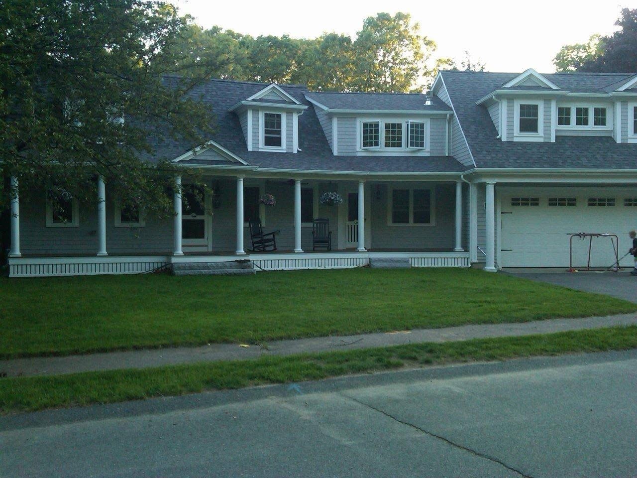 Completed home addition and garage transformation by Boston J's featuring expanded living space, covered front porch with columns, and new exterior