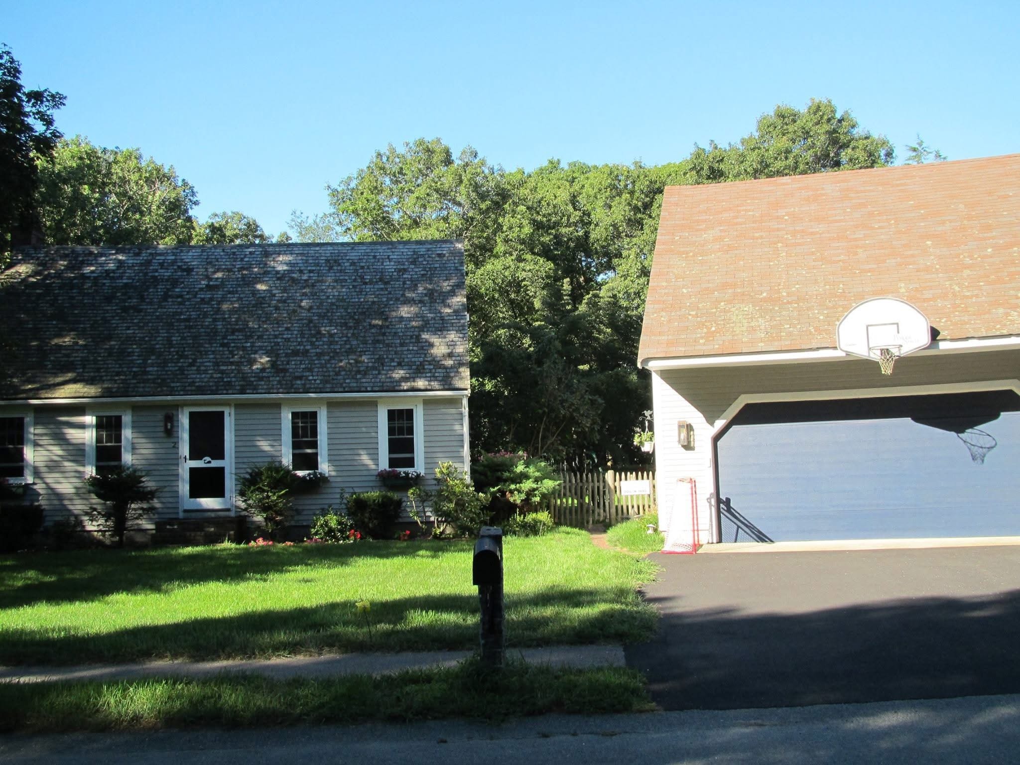 Before photo of a cape-style home with attached garage prior to major transformation by Boston J's
