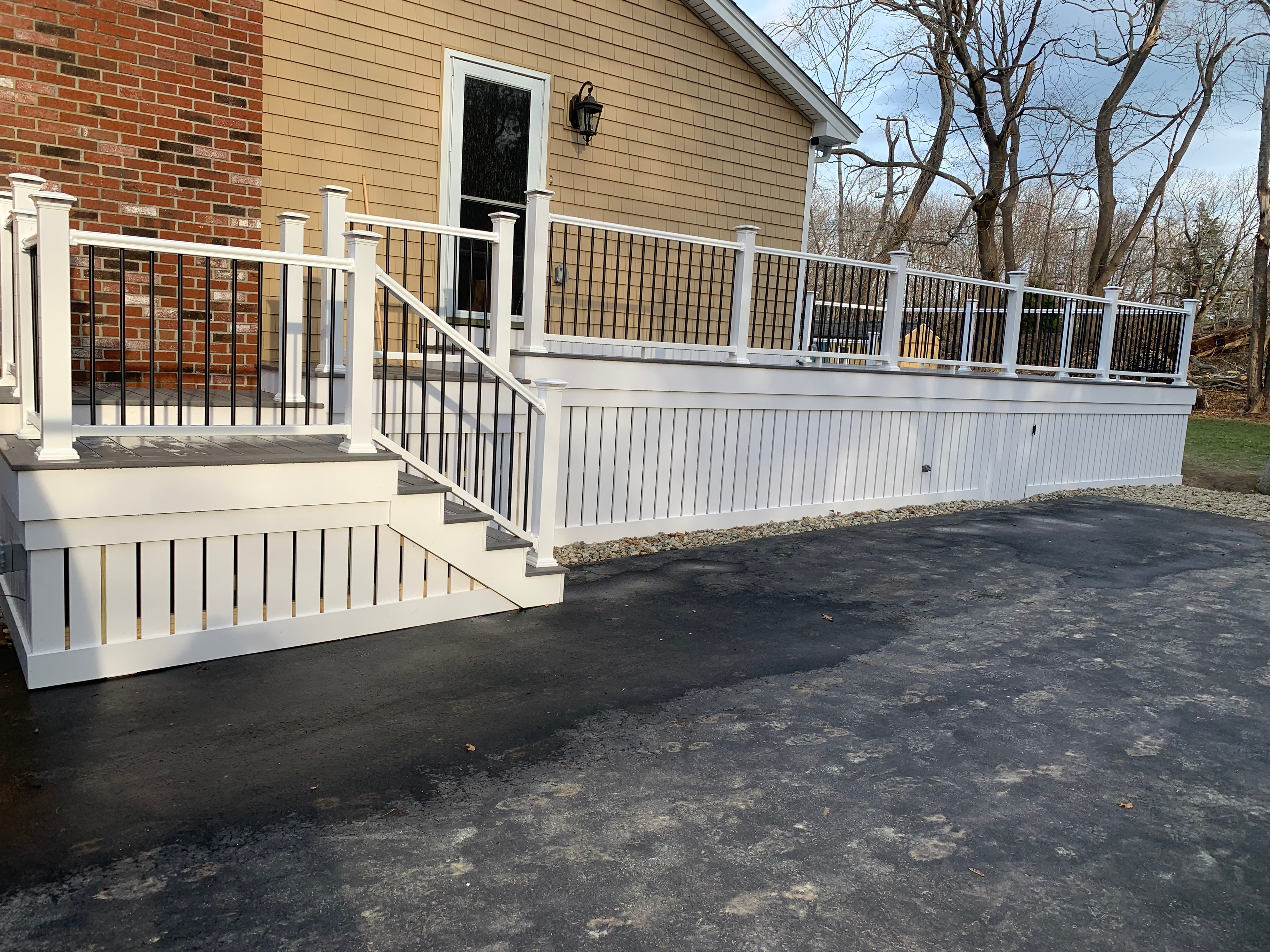 White deck with black balusters and enclosed PVC skirting built by Boston J's Roofing and Construction