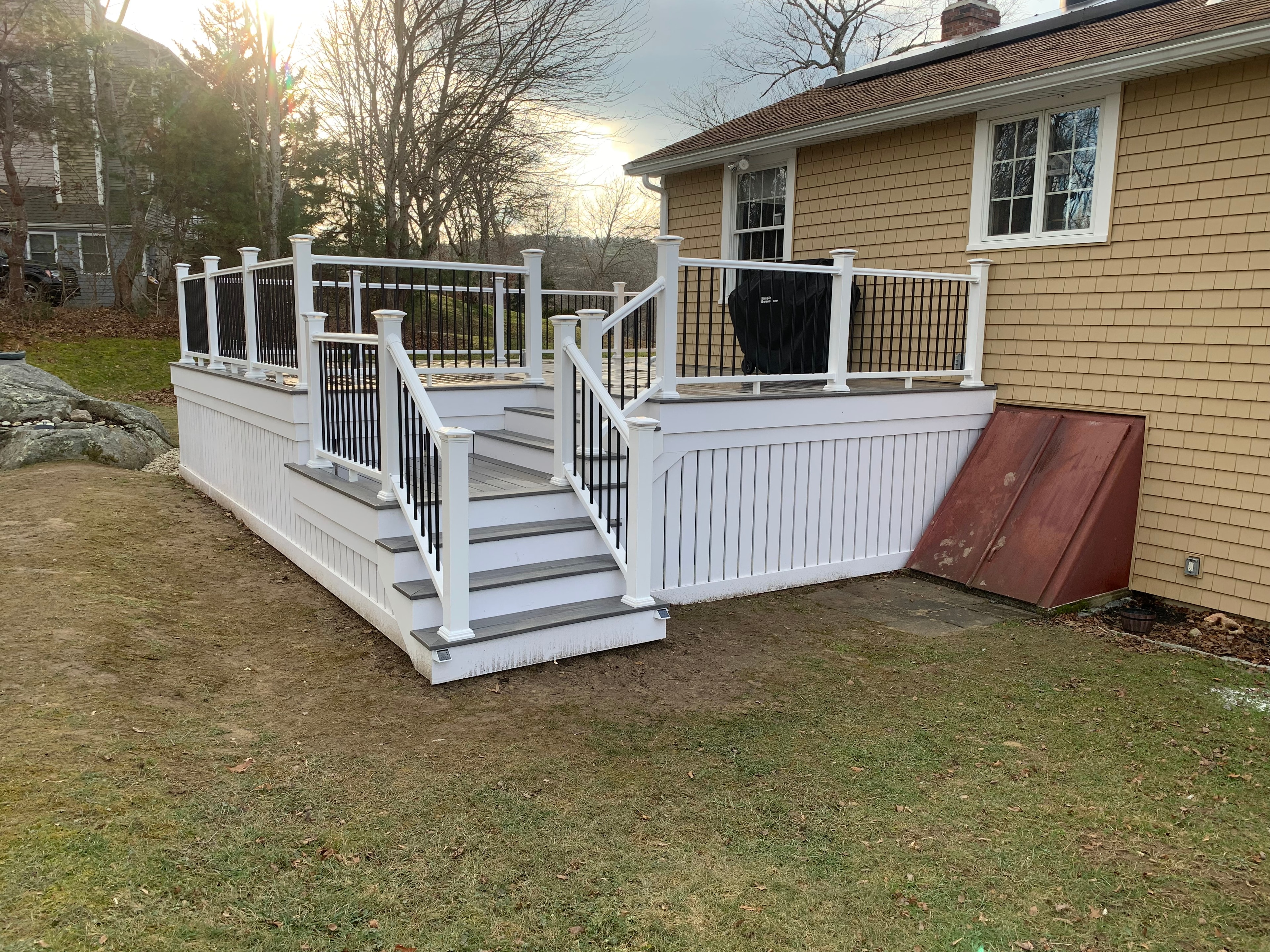 White deck with black balusters and centered staircase built by Boston J's Roofing and Construction