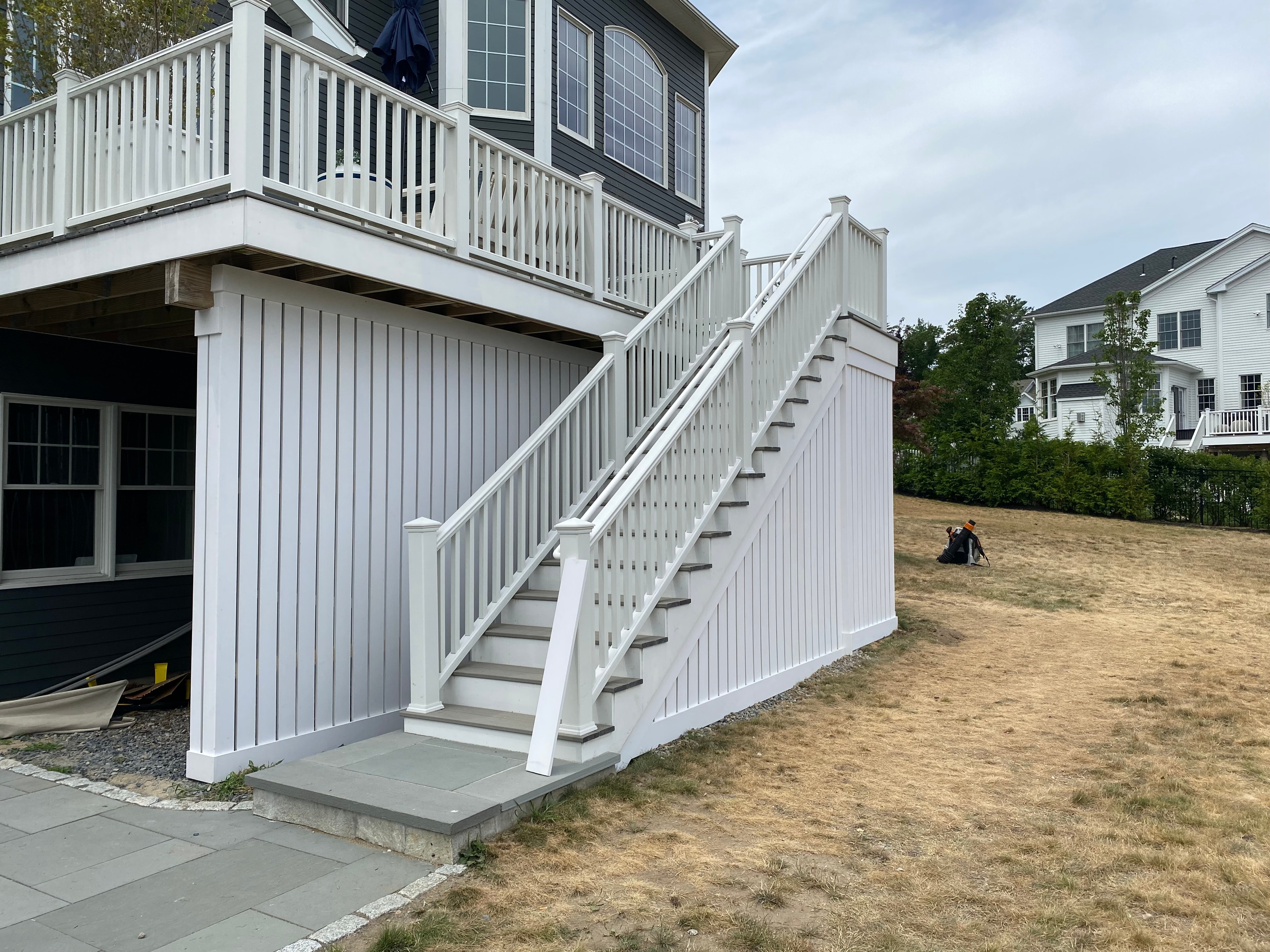 White elevated deck with enclosed PVC skirting and long staircase built by Boston J's