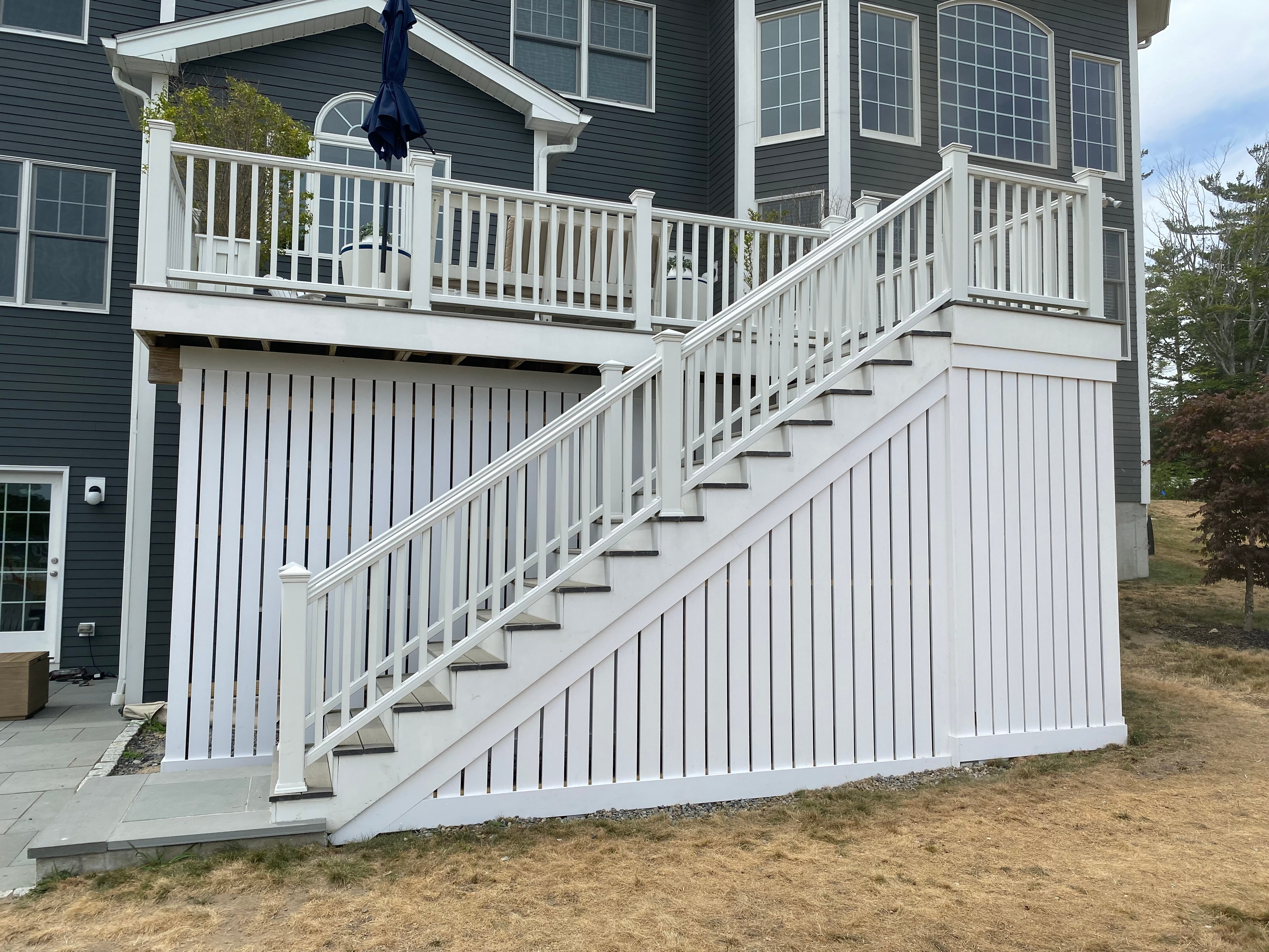 Alternate view of white elevated deck with enclosed PVC skirting built by Boston J's Roofing and Construction