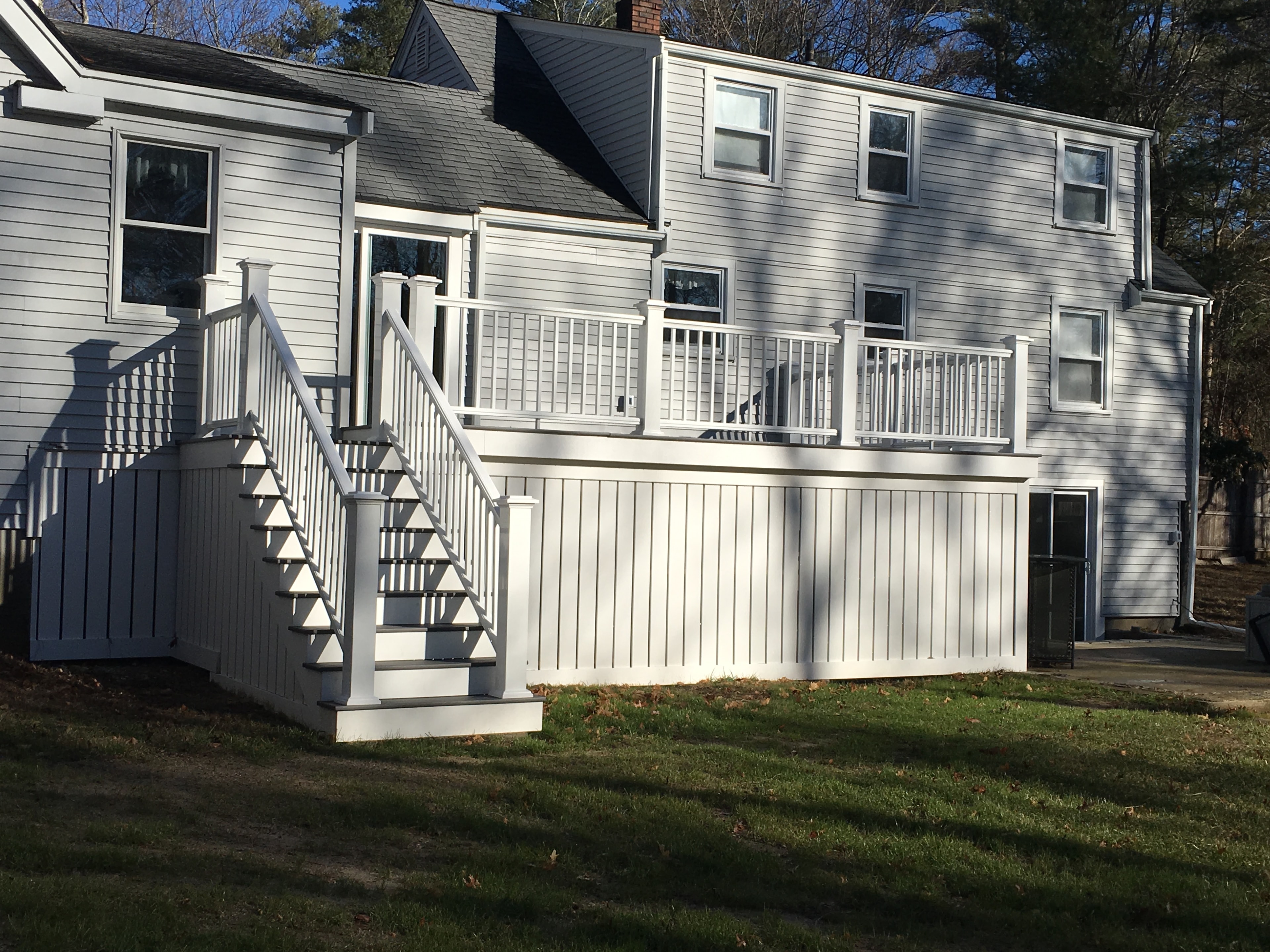 White deck with enclosed PVC skirting and front staircase built by Boston J's Roofing and Construction