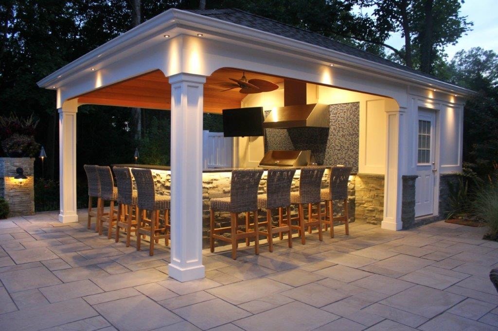 Illuminated poolside kitchen pavilion with bar seating built by Boston J's Roofing and Construction
