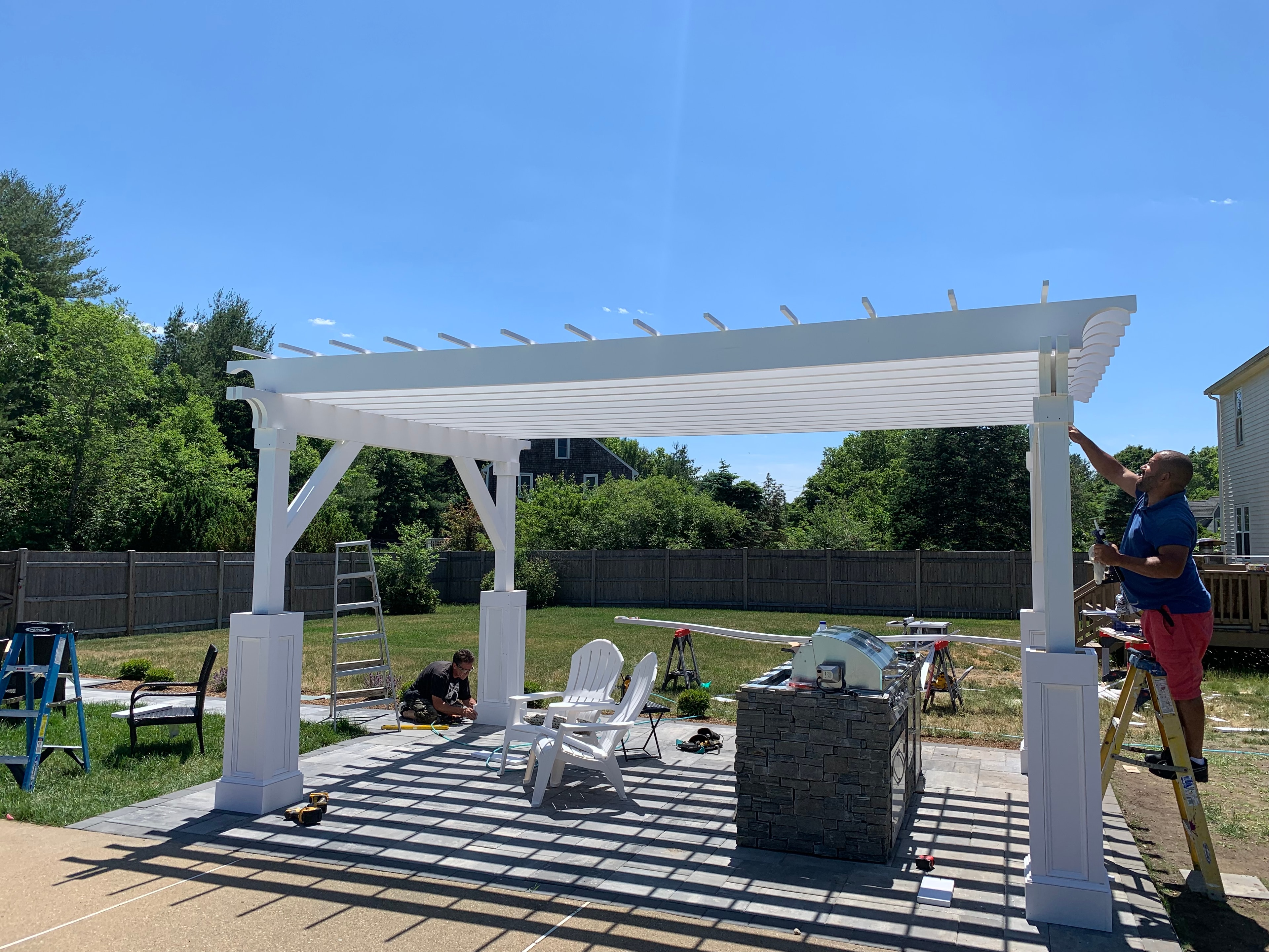 Finished white pergola with outdoor kitchen built by Boston J's Roofing and Construction