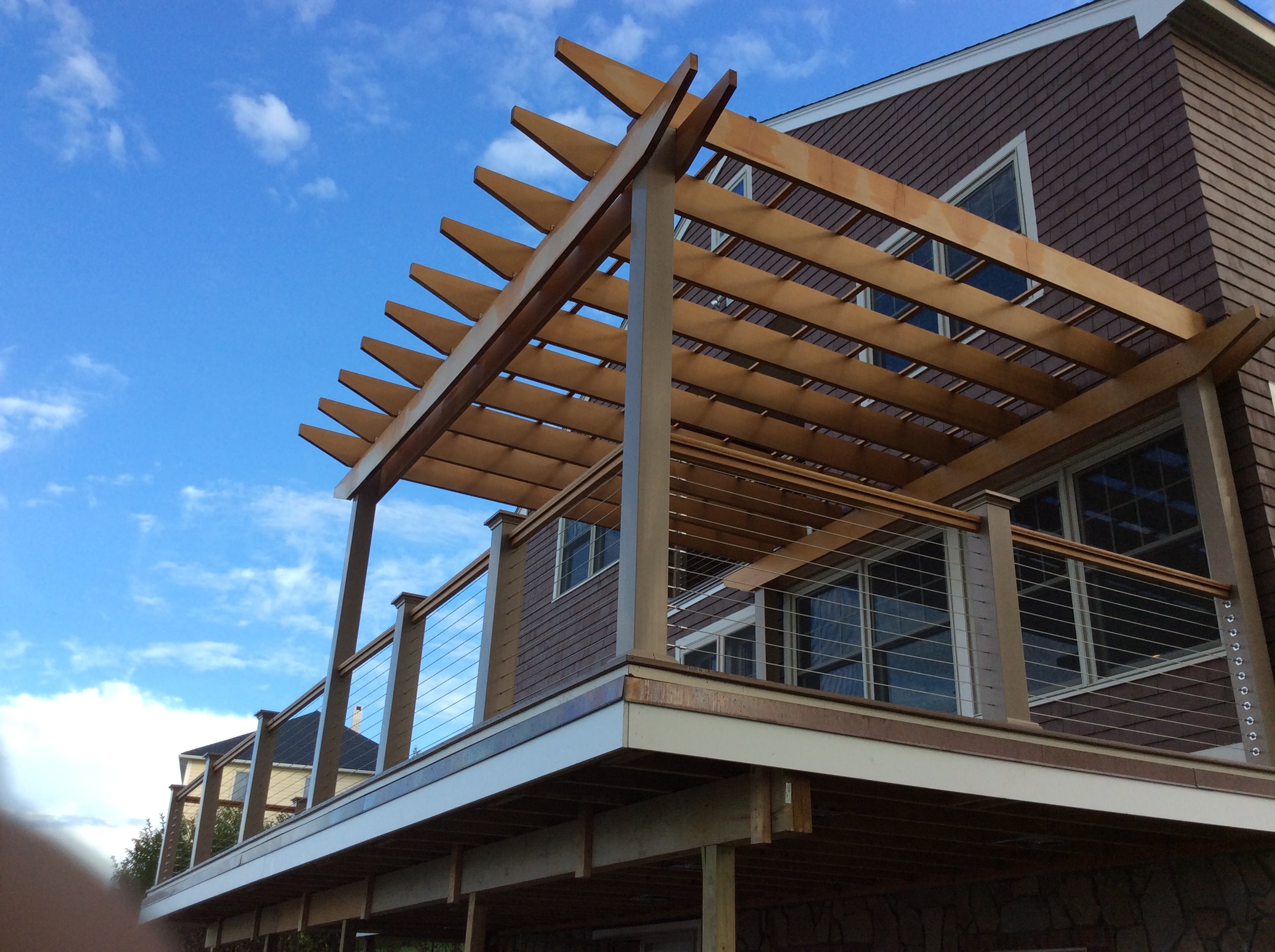 Custom wood pergola over an elevated deck with cable railing built by Boston J's