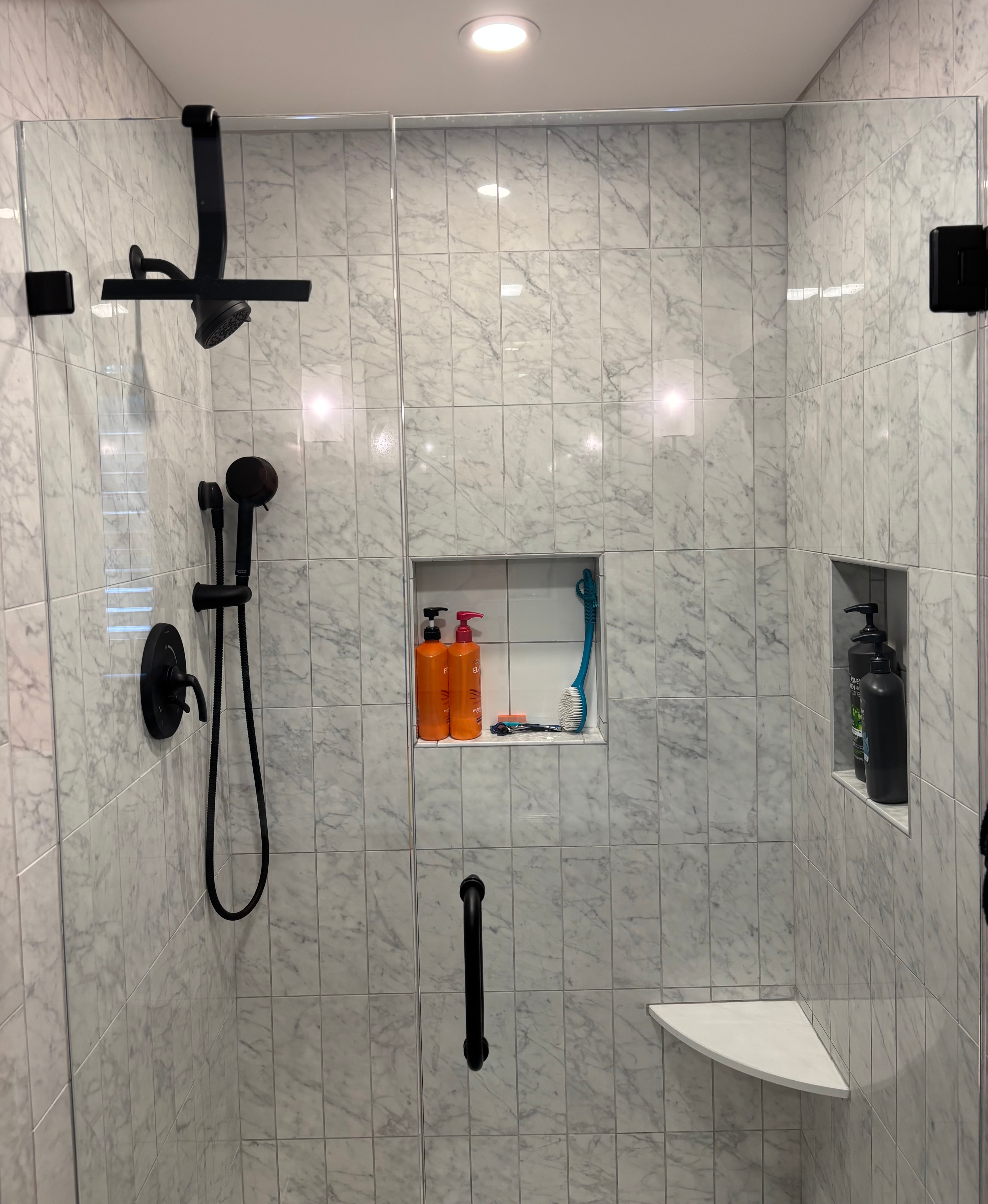 Close-up of two custom recessed shower niches with decorative tile insets completed by Boston J's Roofing and Construction