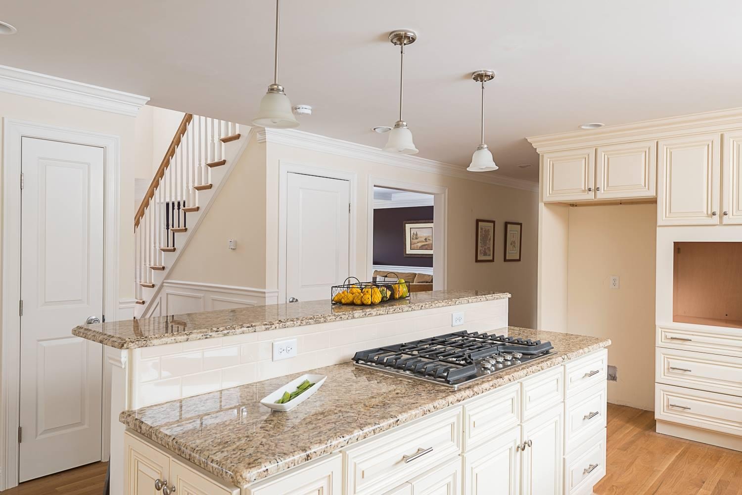 Completed Boston J's kitchen remodel showing island cooktop, stone countertops, custom cabinetry and adjoining dining area