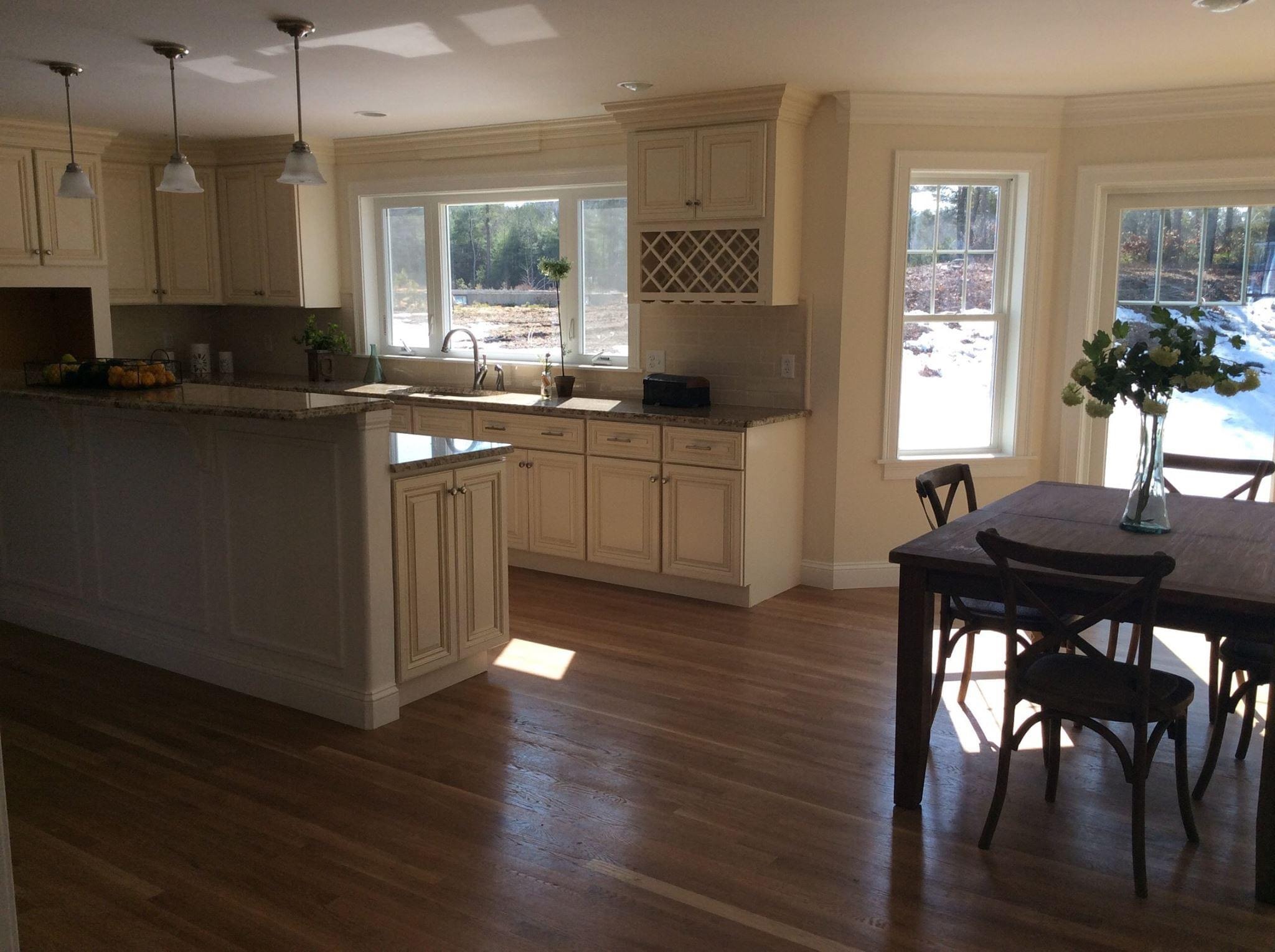 Completed Boston J's kitchen and dining remodel showing custom cabinetry, center island, sink area, hardwood flooring and adjoining dining space