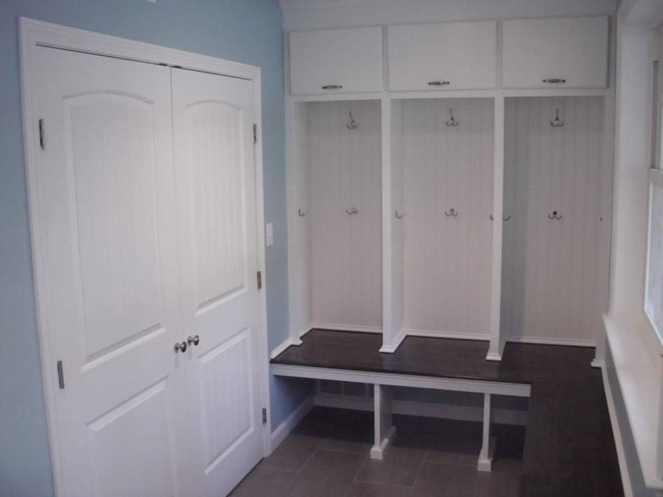 Custom built-in entry unit by Boston J's featuring tall beadboard panels, open shelving, coat hooks, a wood seat and lower storage compartments