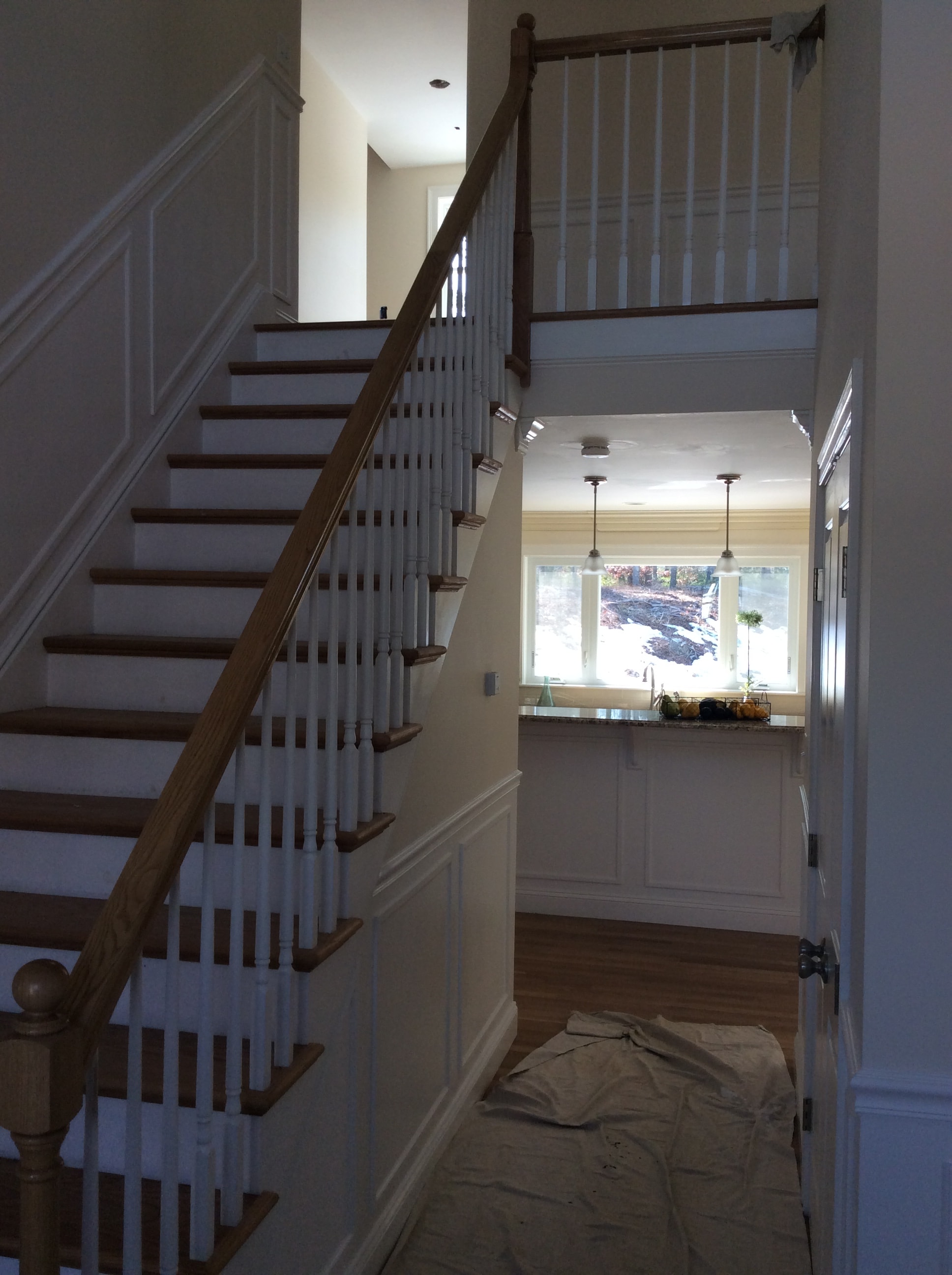 Custom staircase and interior millwork by Boston J's featuring wood treads, wood handrail, white balusters, newel posts and decorative wall paneling