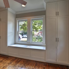 Custom built-in window seat framed by tall fitted storage cabinets completed by Boston J's